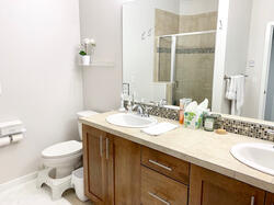 Spa-style bath with double sinks, tiled shower, and handheld shower head for added comfort