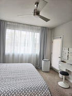 Primary bedroom with portable A/C, ceiling fan, and private balcony access